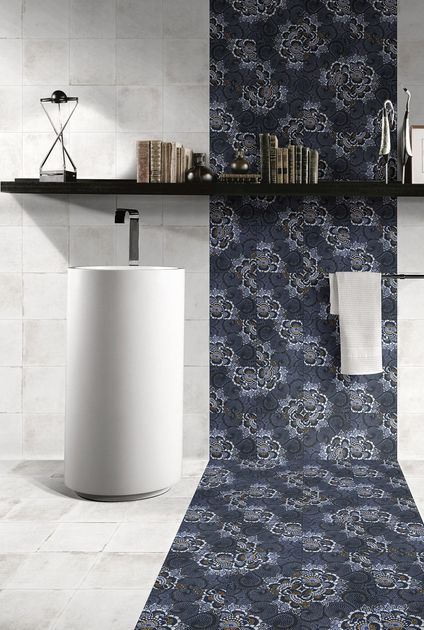 Bagno con lavabo bianco su piedistallo, pavimento piastrellato e parete decorativa con motivo blu scuro.
