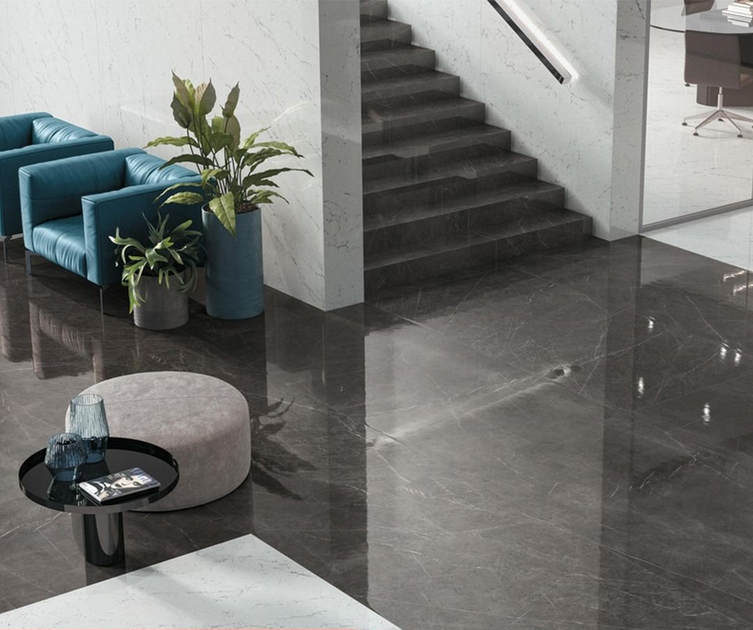 Atrio con sedie color verde acqua, piante in vaso e pavimenti in marmo grigio scuro che conducono a una scala.