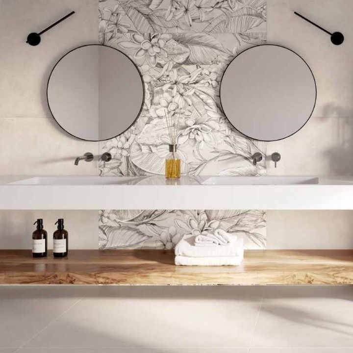 Bagno con doppi lavandini, specchi rotondi, paraschizzi con piastrelle floreali, mensola in legno e oggetti decorativi.