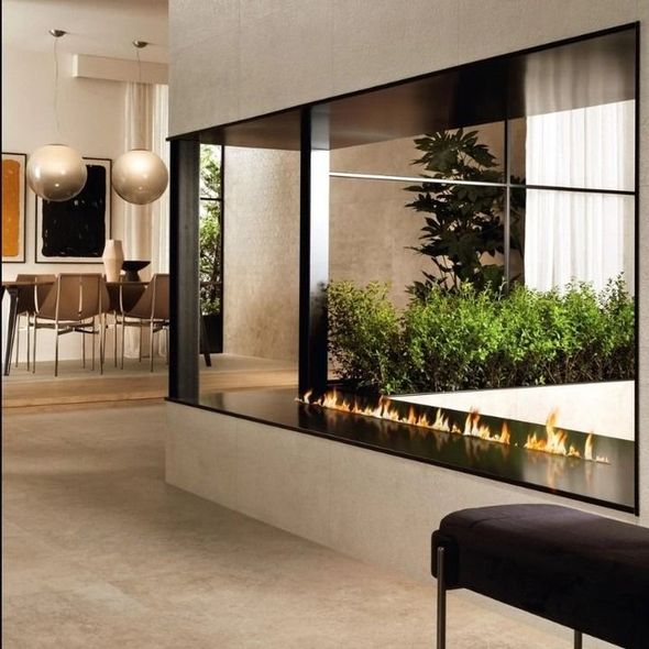 Soggiorno moderno con camino lineare, finestra con cornice nera che si affaccia sul giardino e arredamento contemporaneo.