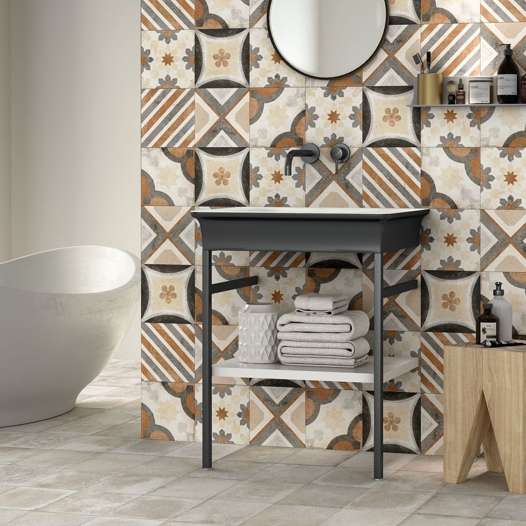 Bagno con piastrelle a motivi, lavandino nero, vasca bianca e sgabello in legno.