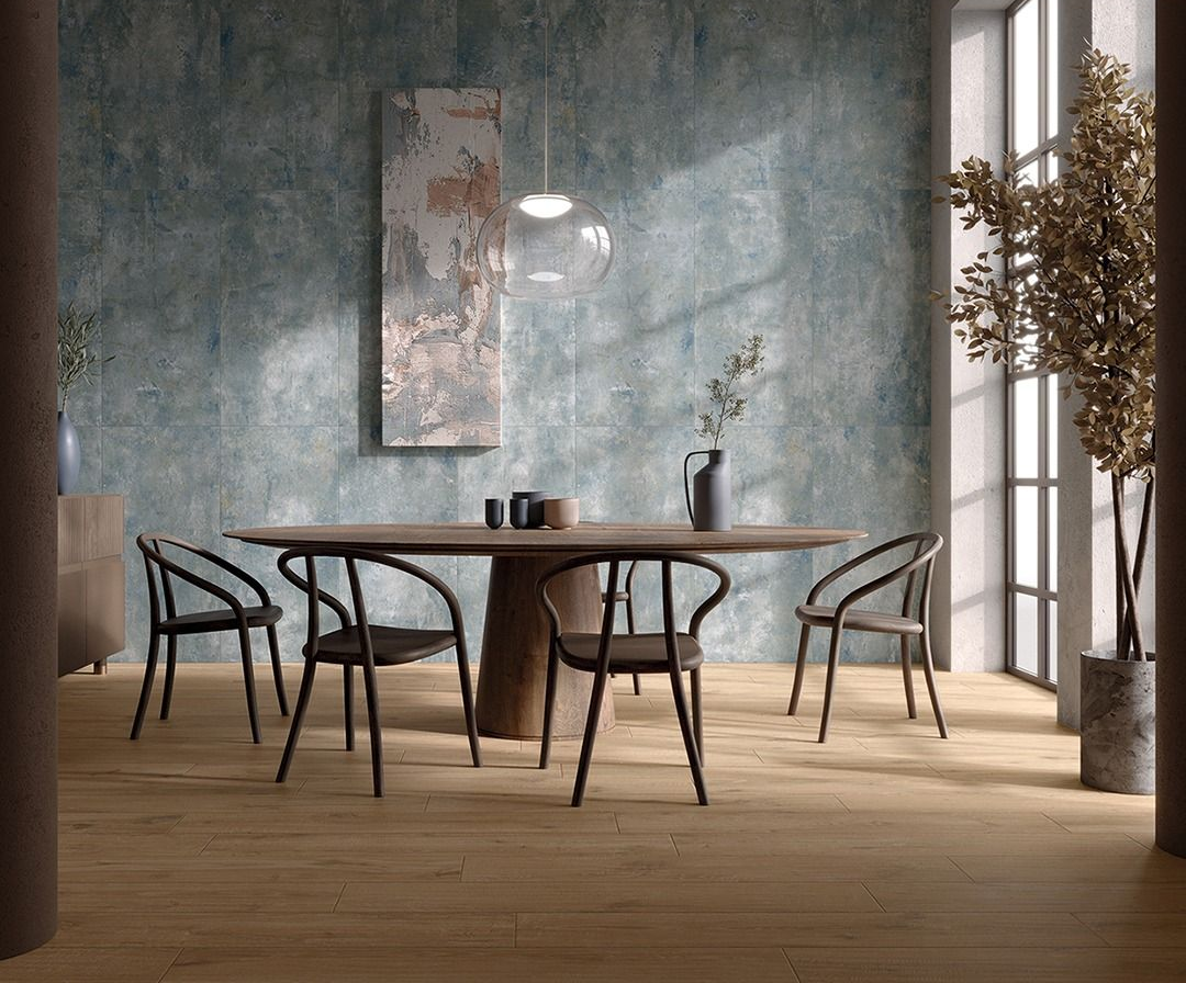 Sala da pranzo con tavolo ovale, sedie nere, parete con texture blu e pavimento in legno.