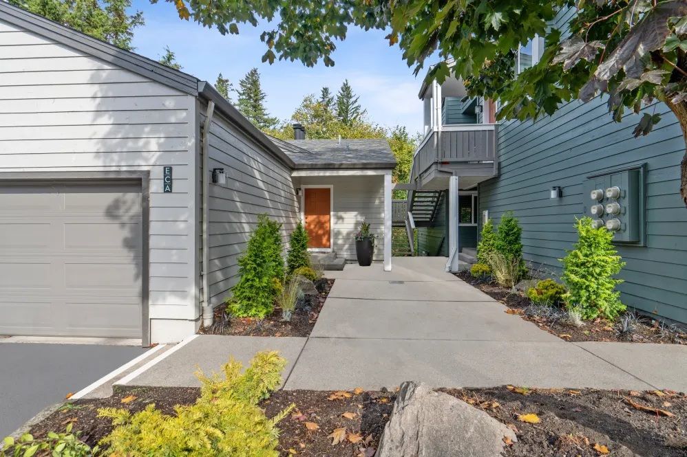 Gray house exterior with garage, walkway, and landscaping.