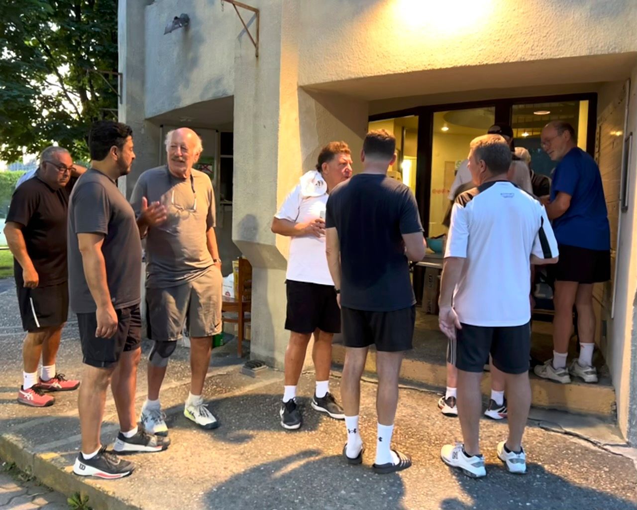 A group of men are standing outside of a building talking