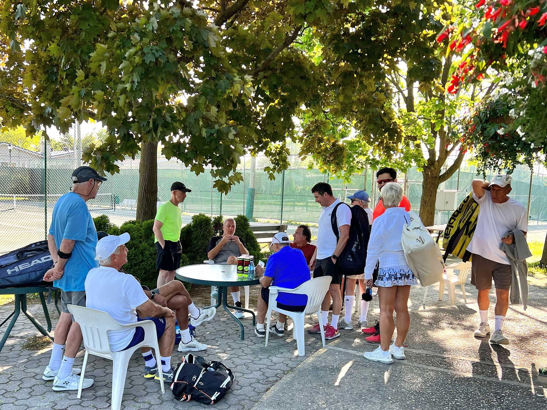 A group of people are sitting around a table under a tree