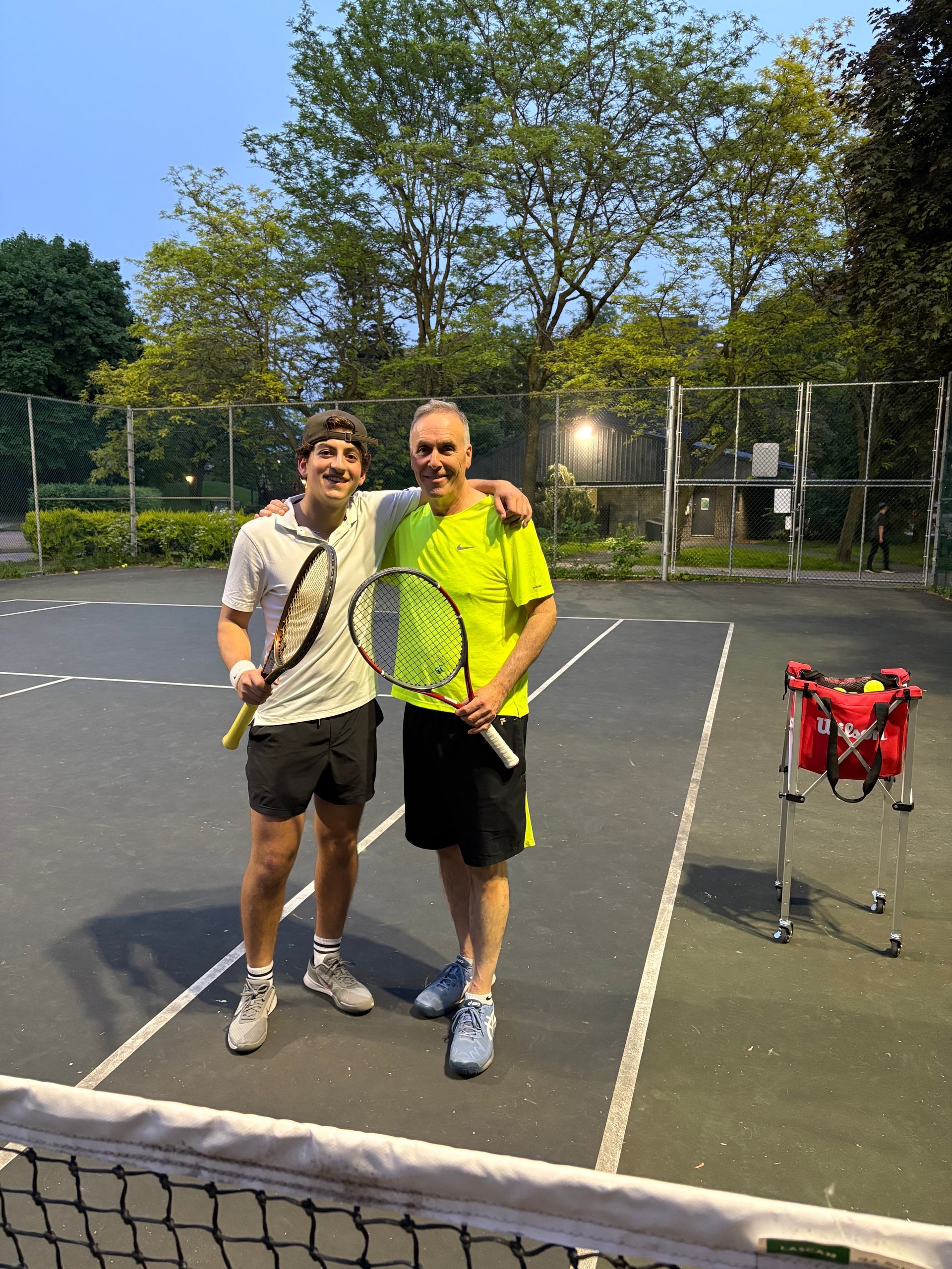 Two men are posing for a picture on a tennis court
