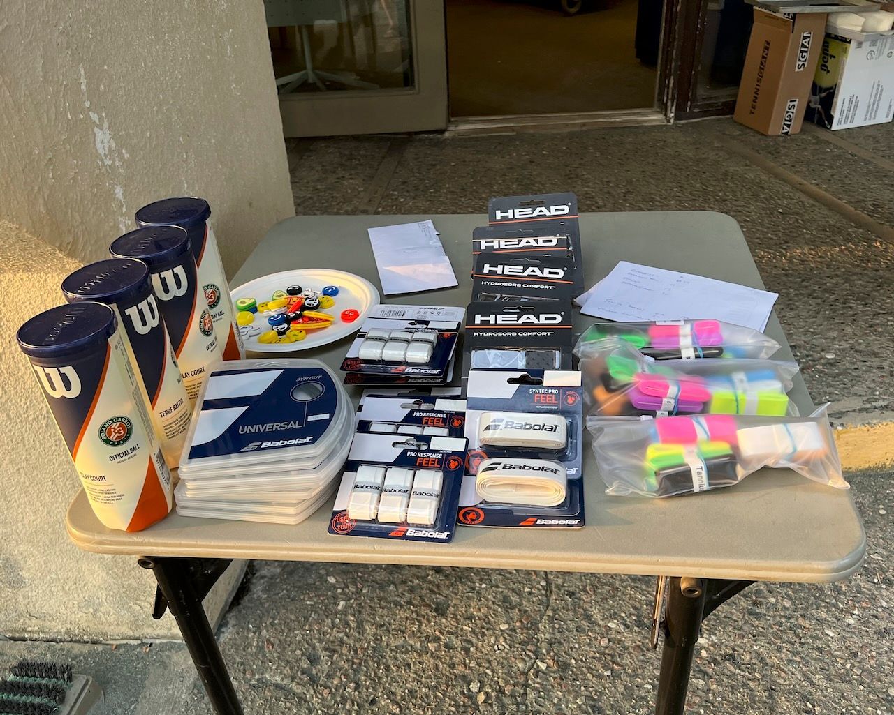 A table with a stack of wilson tennis balls and other tennis items on it