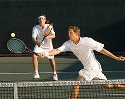 Two men are playing tennis on a tennis court.