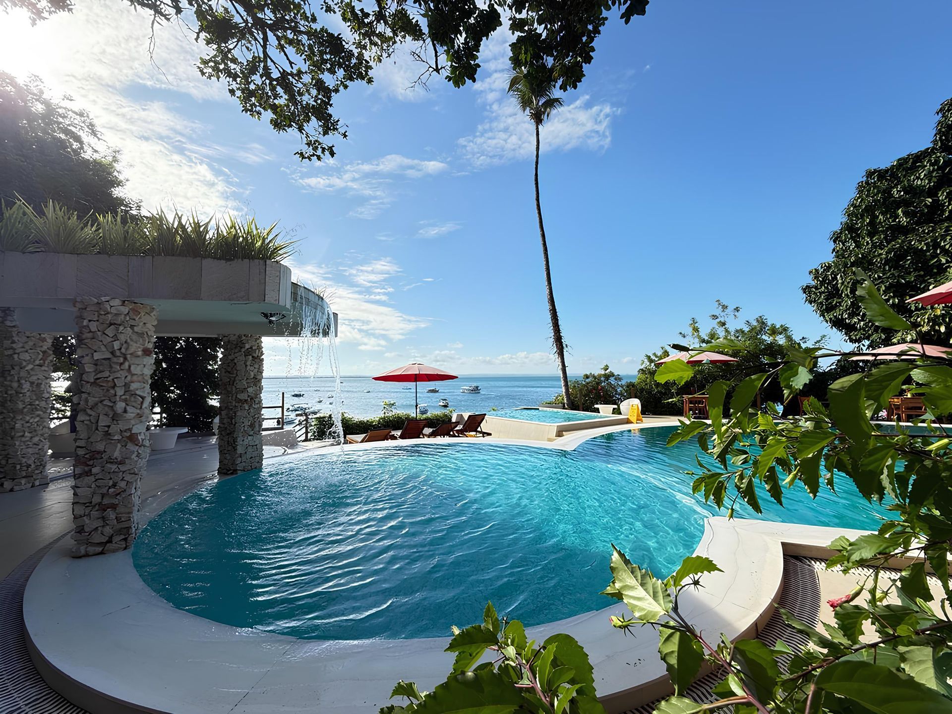 Uma grande piscina rodeada por cadeiras e mesas com vista para o oceano Hotel Portaló