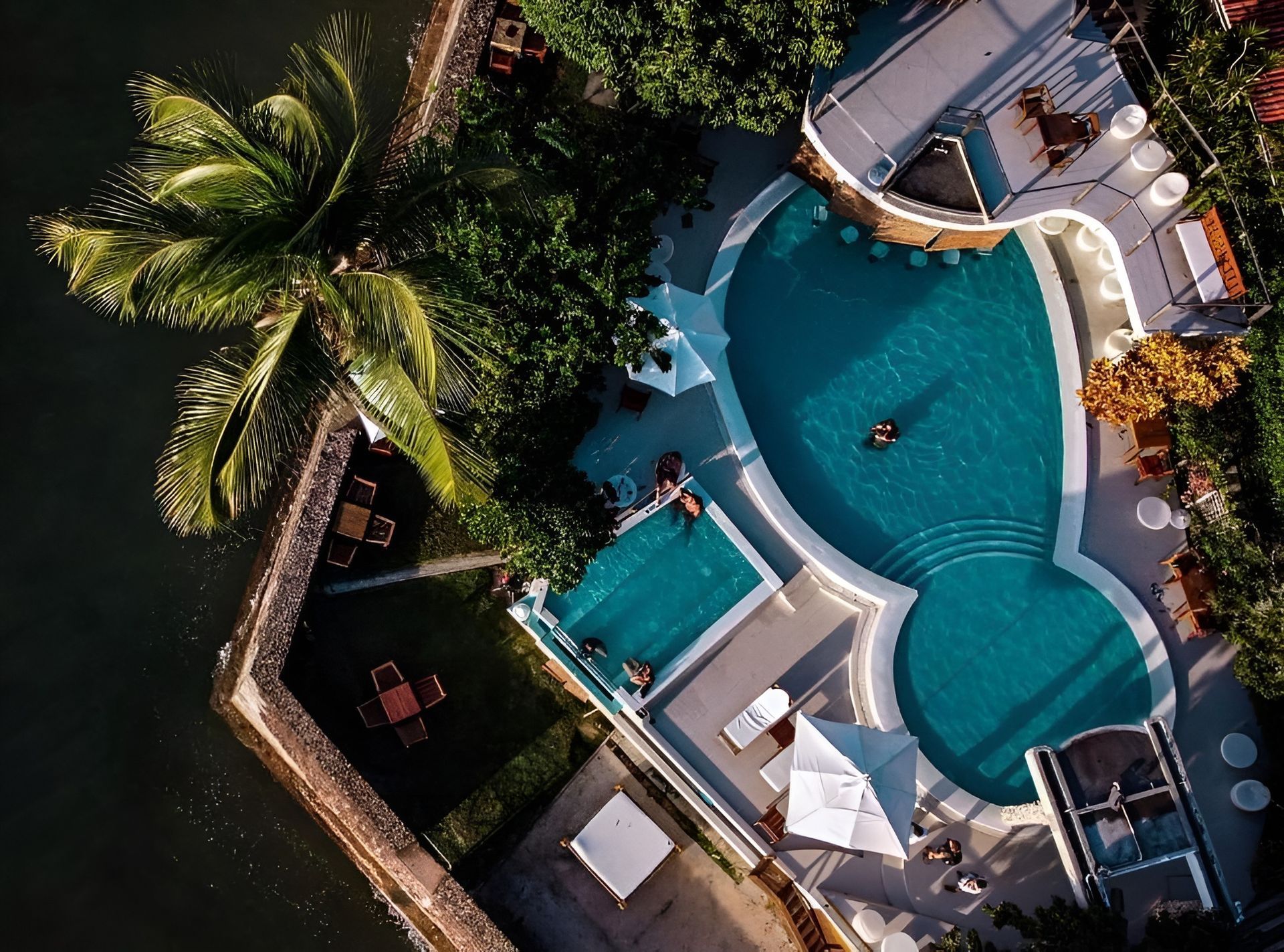 Uma vista aérea de uma grande piscina cercada por palmeiras Hotel Portaló