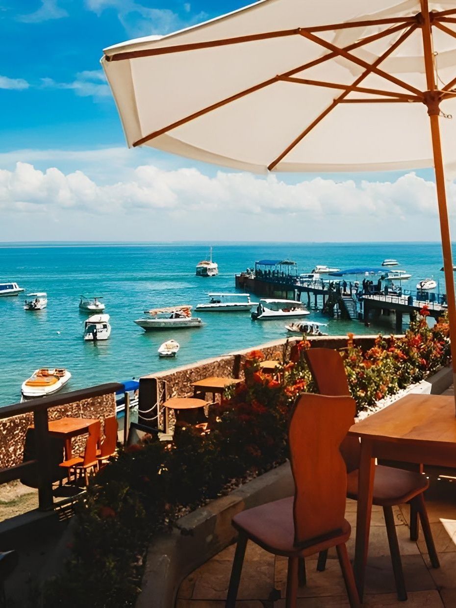 Uma mesa e cadeiras sob um guarda-sol com vista para o oceano Hotel Portaló