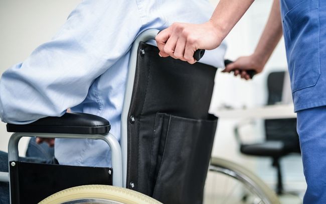 caregiver pushing elder person in wheelchair