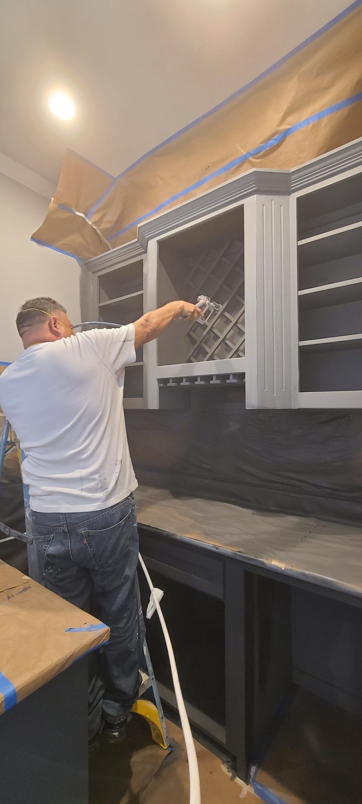 A man is painting cabinets in a kitchen.