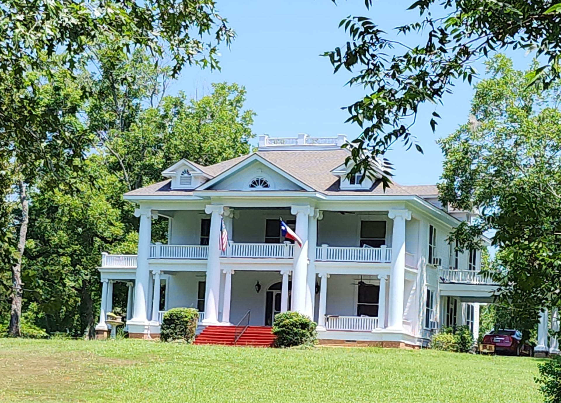 A large white house with a red carpet on the porch