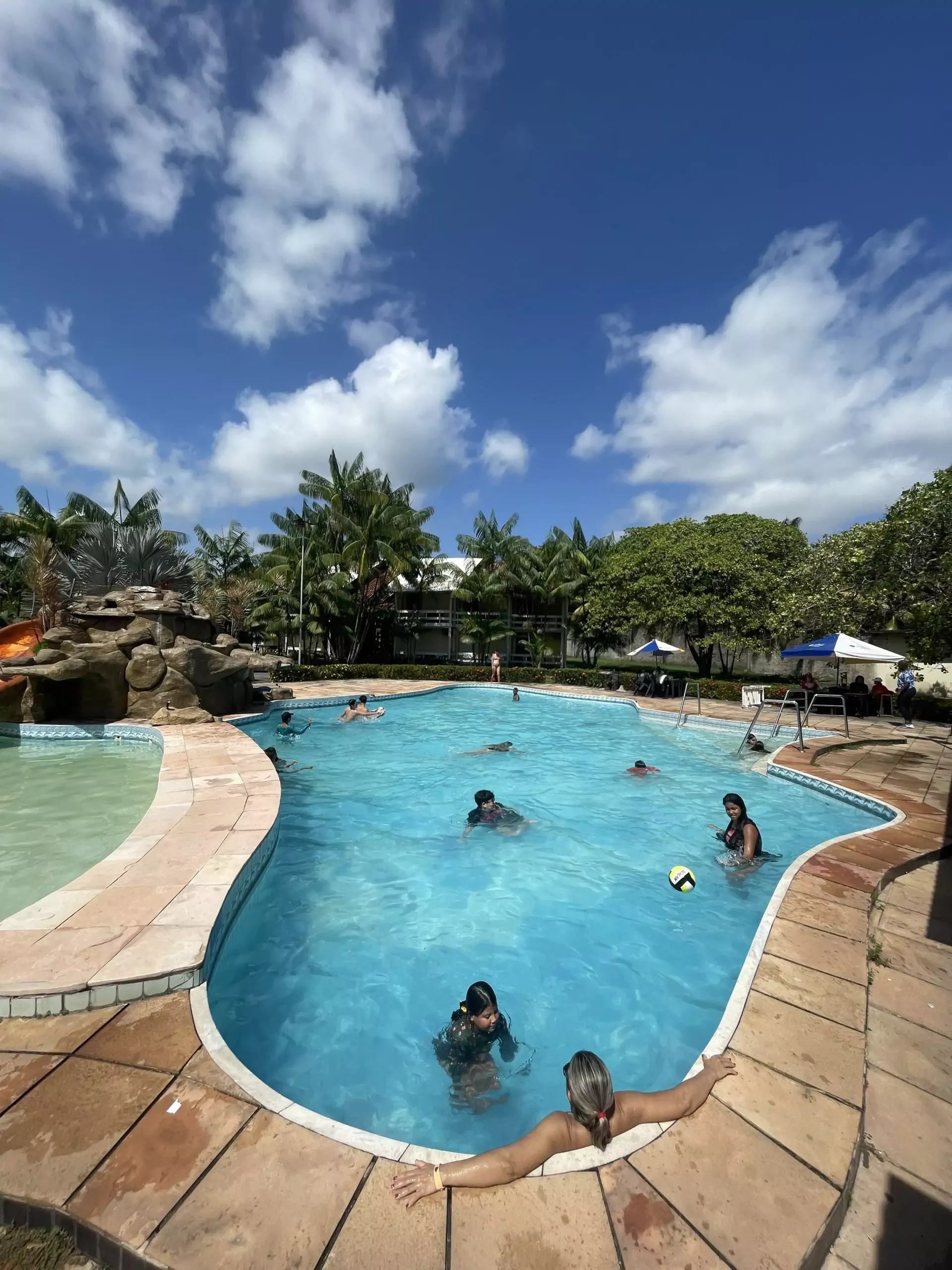 Um abajur está sobre uma mesa de madeira ao lado de uma cama.-go-organic-club