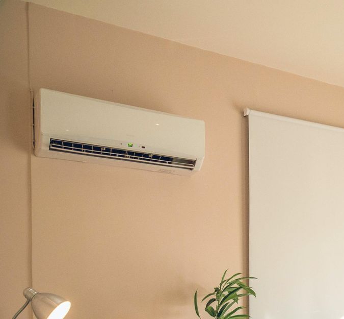 Uma pessoa está segurando um controle remoto na frente de um ar condicionado.-go-organic-club