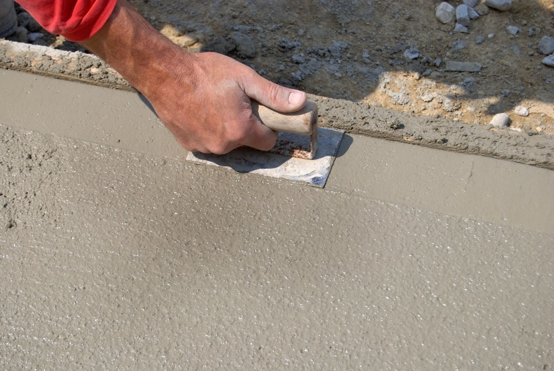 Person in boots smoothing wet concrete with a screed. Person in boots smoothing wet concrete with a screed.