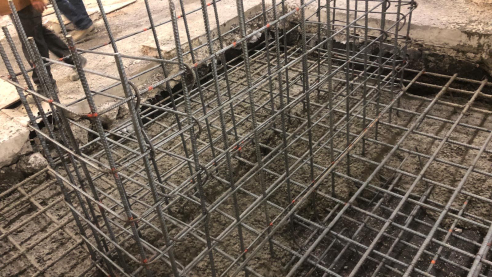 Reinforced steel bars forming a grid within a concrete foundation. Reinforced steel framework for concrete construction project.