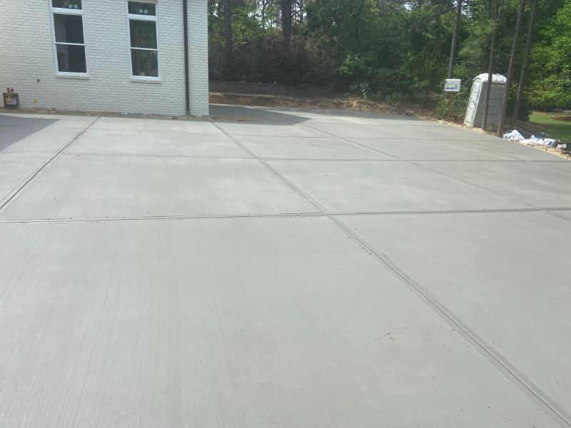 Newly poured concrete driveway with expansion joints in front of a white building.