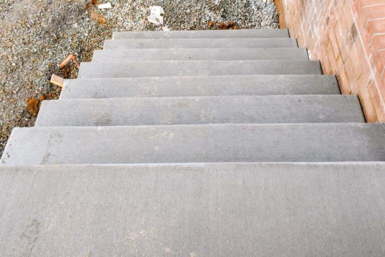Large, octagonal concrete platform inside a concrete enclosure; metal scaffolding and stairs visible. Gray concrete stairs viewed from above, leading downwards.