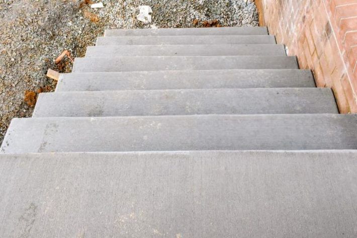 Large, octagonal concrete platform inside a concrete enclosure; metal scaffolding and stairs visible. Gray concrete stairs viewed from above, leading downwards.