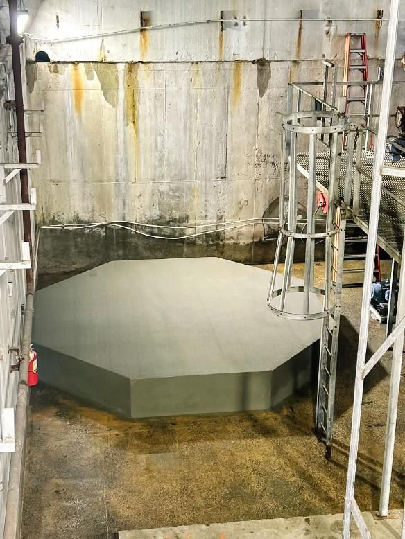 Large, octagonal concrete platform inside a concrete enclosure; metal scaffolding and stairs visible. Large, octagonal concrete platform inside a concrete enclosure; metal scaffolding and stairs visible.