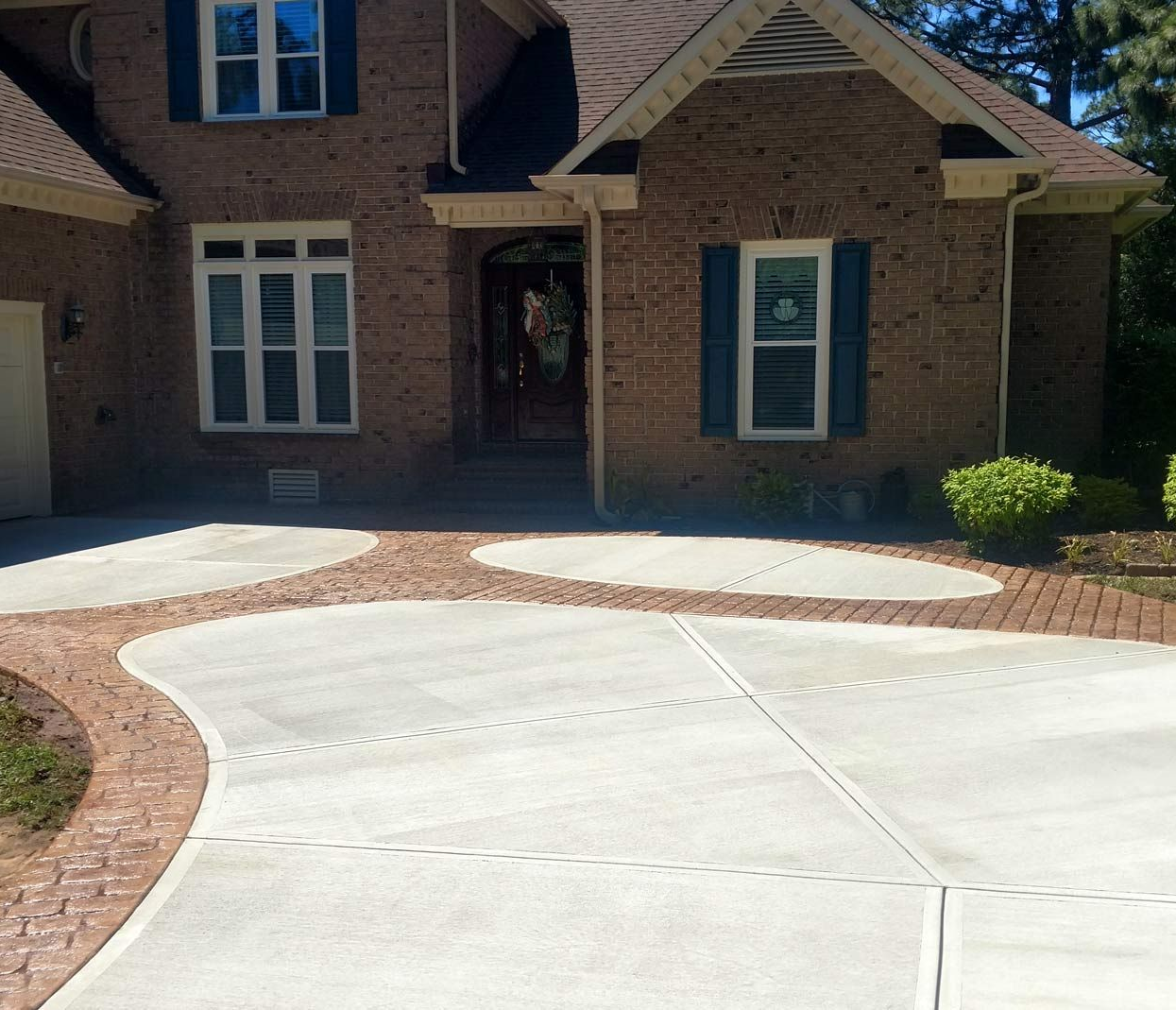 Concrete patio with a blue rectangular pool surrounded by trees. White chairs stacked on the right. Concrete patio surrounds a blue rectangular pool; trees and a building are in the background.