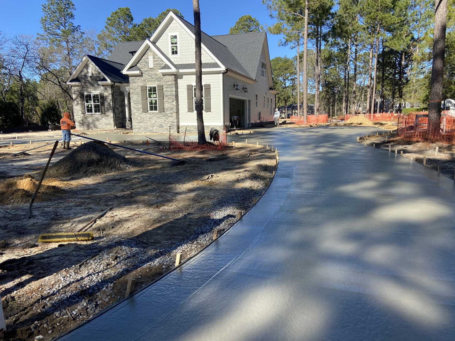 New concrete driveway being laid in front of a new house under construction.