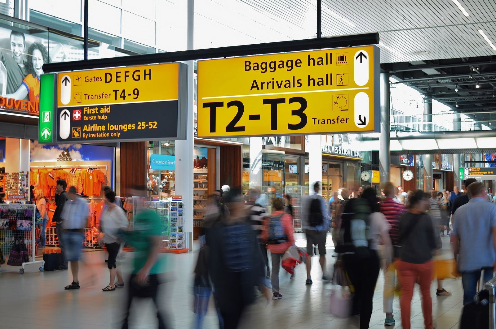A group of people are walking through an airport with signs for baggage hall and arrivals hall