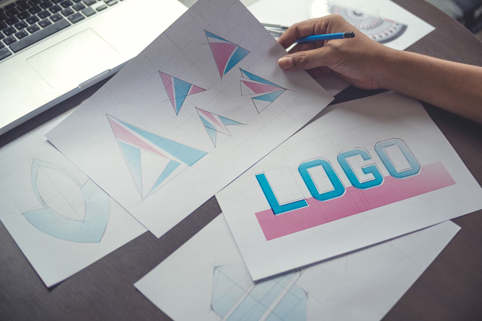 A person is drawing a logo on a piece of paper.