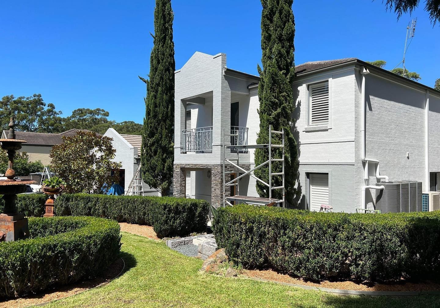 A Man in an Orange Vest is Standing in Front of a White Building — D & J Saverino Painting & Decorating Pty Ltd In Fairy Meadow, NSW