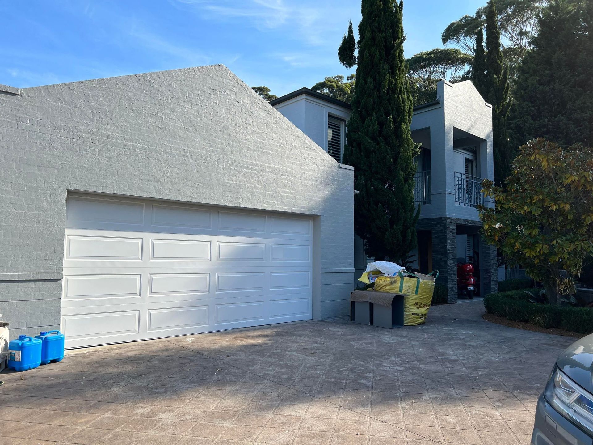 A car is parked in front of a large white garage door — D & J Saverino Painting & Decorating Pty Ltd In Fairy Meadow, NSW