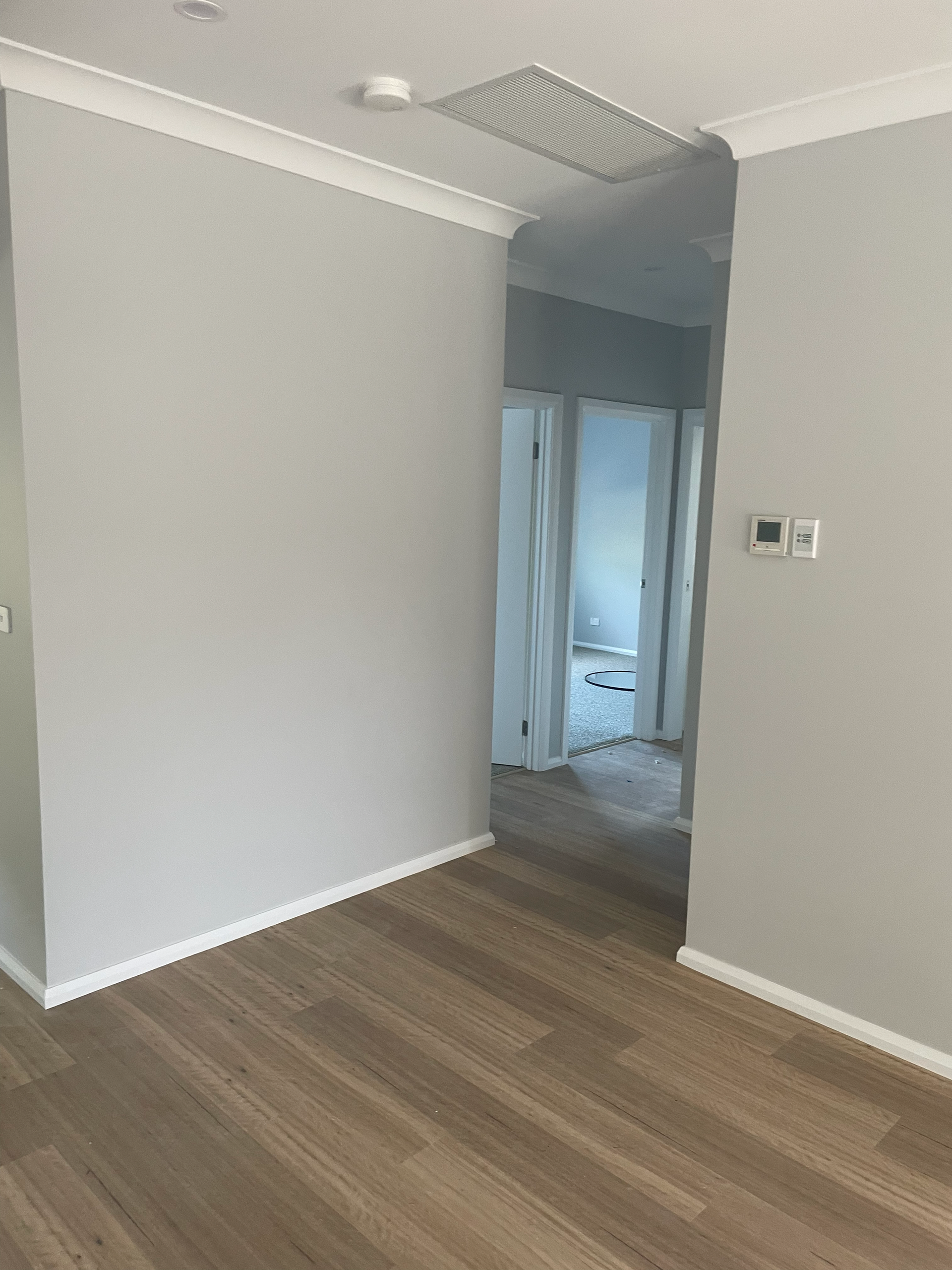 An empty room with hardwood floors and white walls — D & J Saverino Painting & Decorating Pty Ltd In Fairy Meadow, NSW