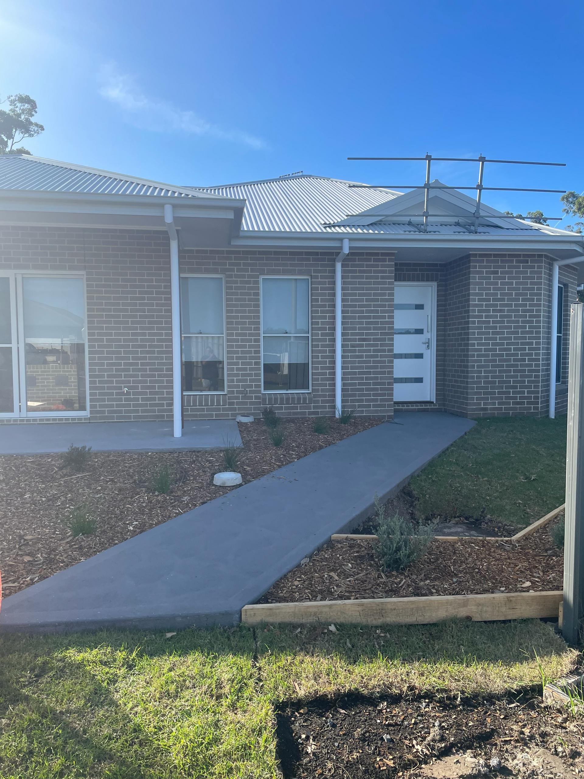 A brick house with a walkway leading to it and a blue sky in the background — D & J Saverino Painting & Decorating Pty Ltd In Fairy Meadow, NSW