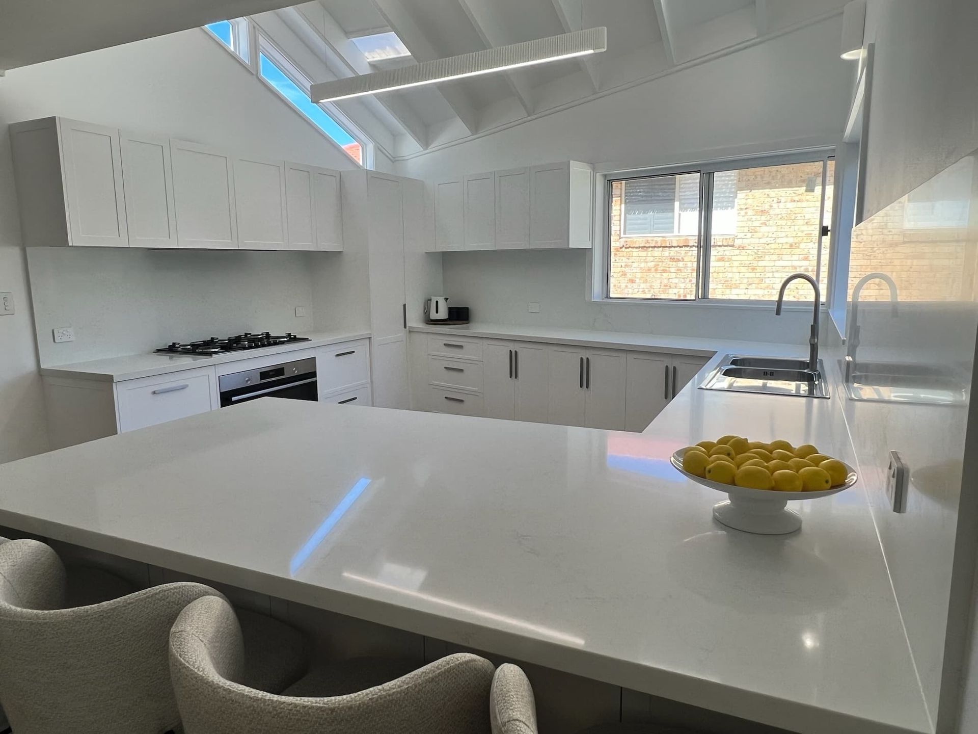 A kitchen with white cabinets and a bowl of lemons on the counter — D & J Saverino Painting & Decorating Pty Ltd In Fairy Meadow, NSW