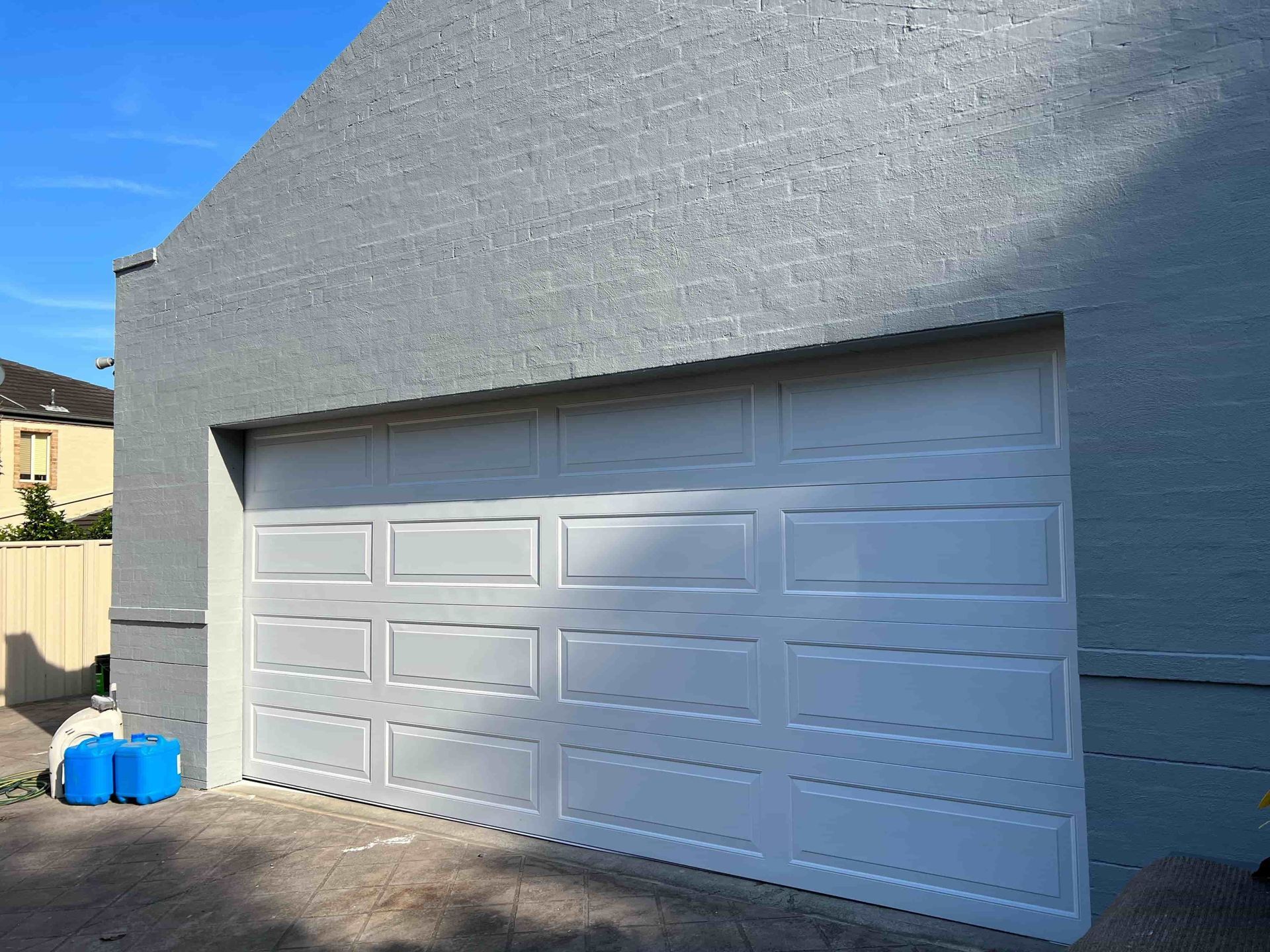 A white garage door is sitting on the side of a building — D & J Saverino Painting & Decorating Pty Ltd In Fairy Meadow, NSW