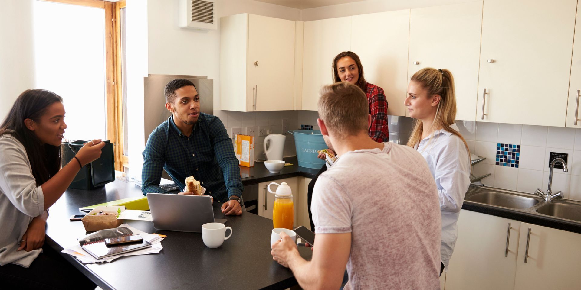 A group of people are sitting around a table in a kitchen.
