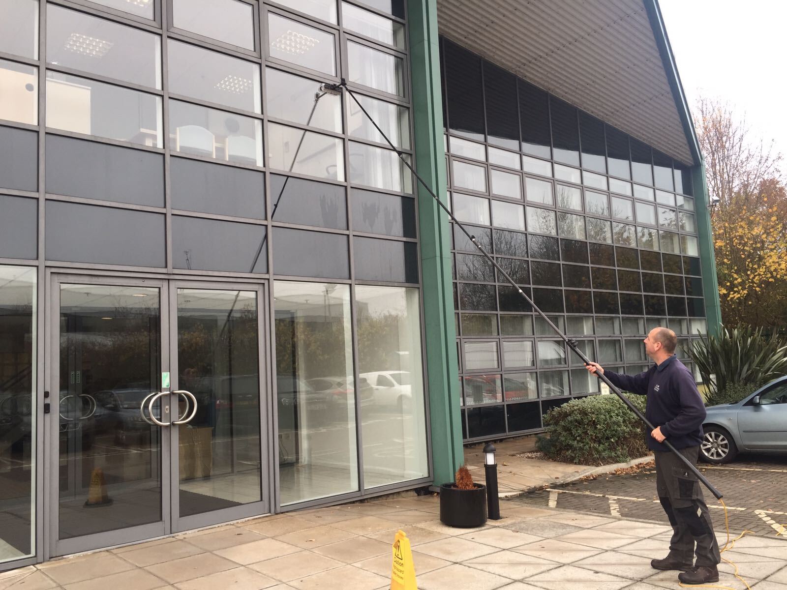 A man is cleaning the windows of a building with a hose.