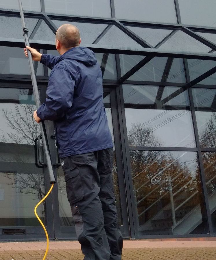 A man in a blue jacket is cleaning a building