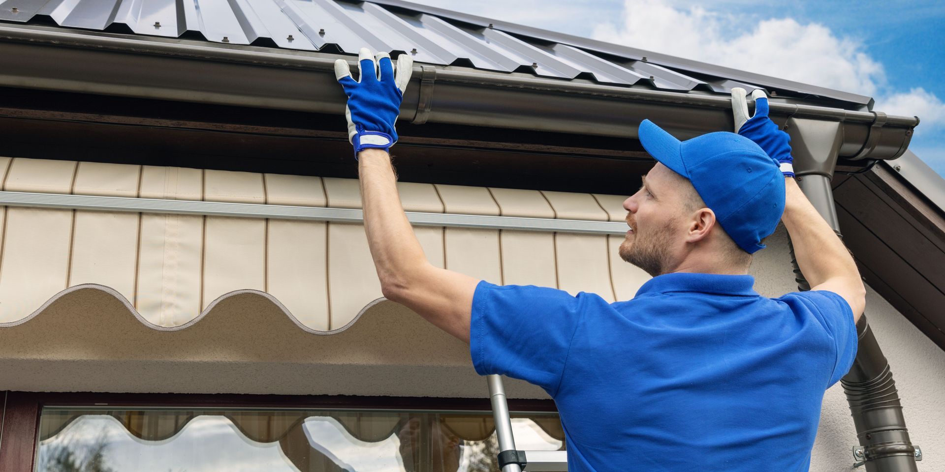 A man is fixing a gutter on the roof of a house.