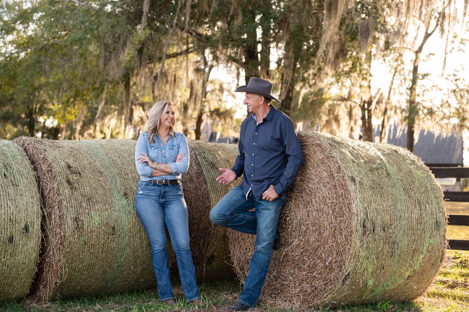 A man and a woman are leaning against a bale of hay.