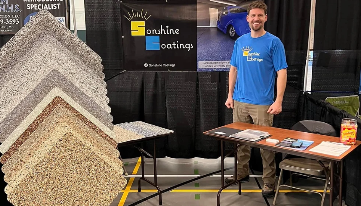 Sonshine Coatings owner Sonny Peterson in a blue shirt standing by color samples of the coatings.