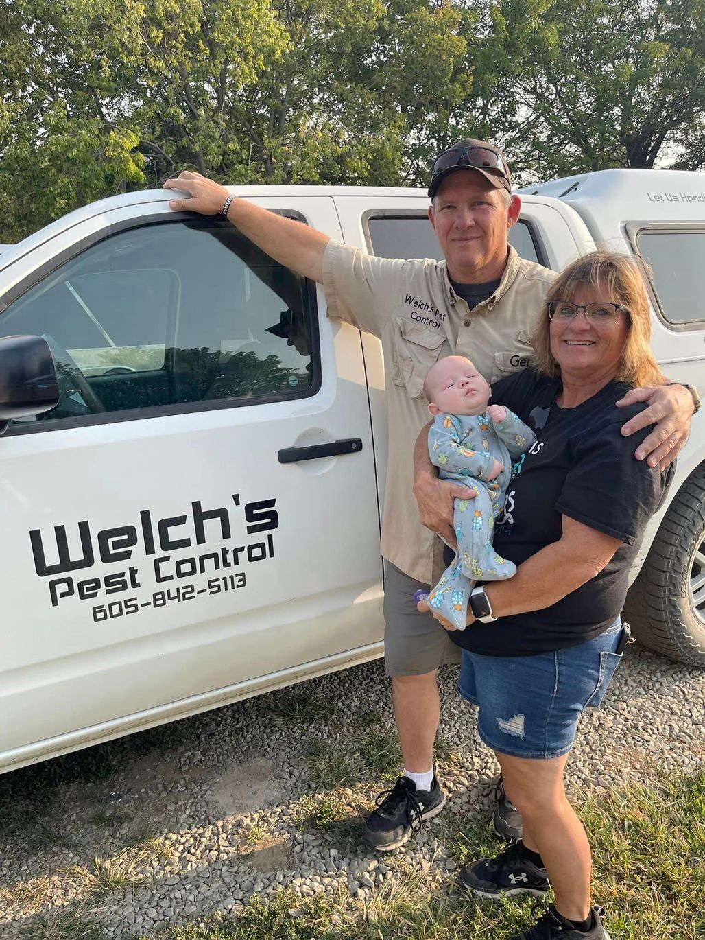 A man and woman are holding a baby in front of a truck.