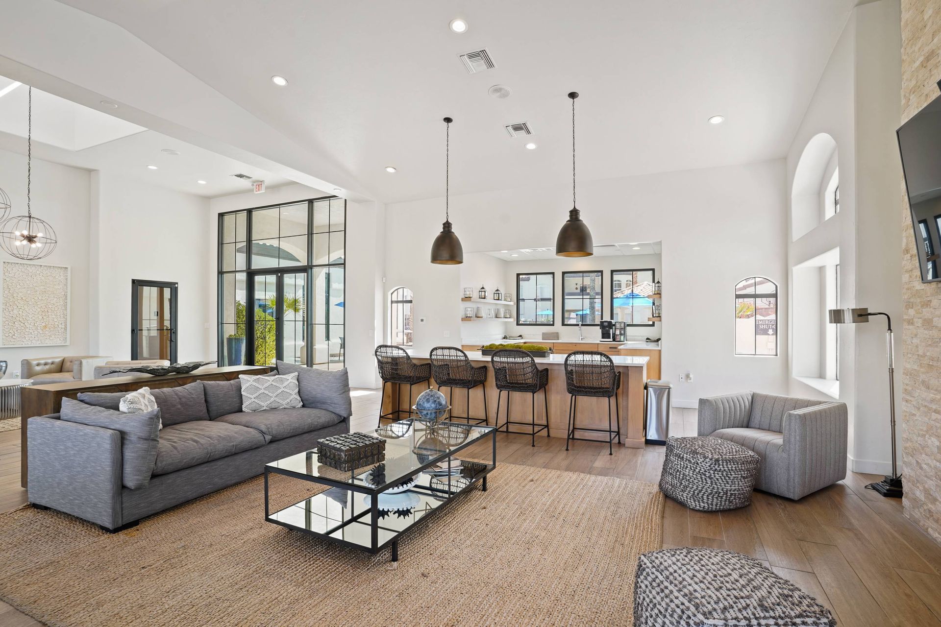 Bright modern community lounge with sofa seating, a bar area, and large windows.