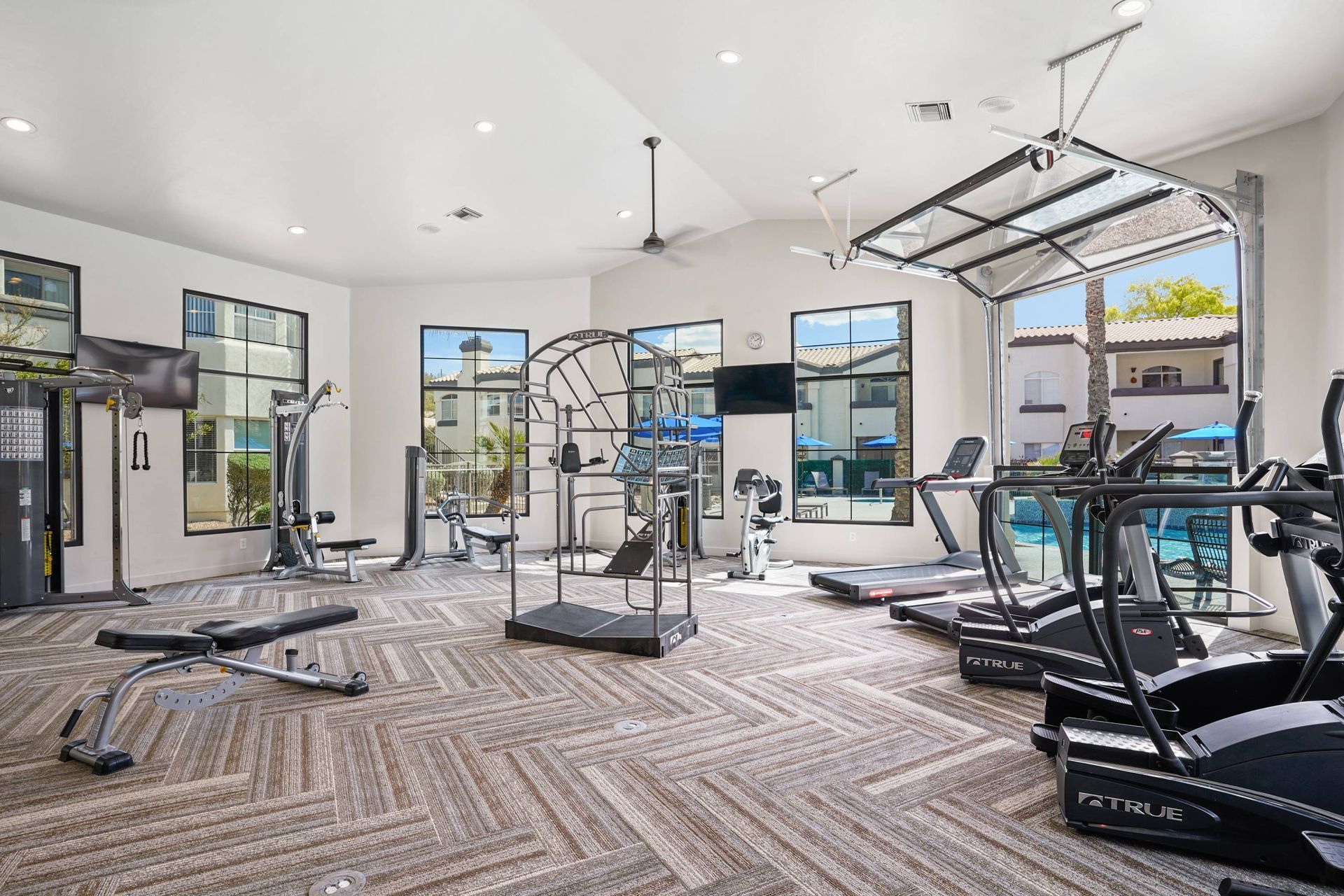 Bright residential gym with cardio machines and weight equipment.