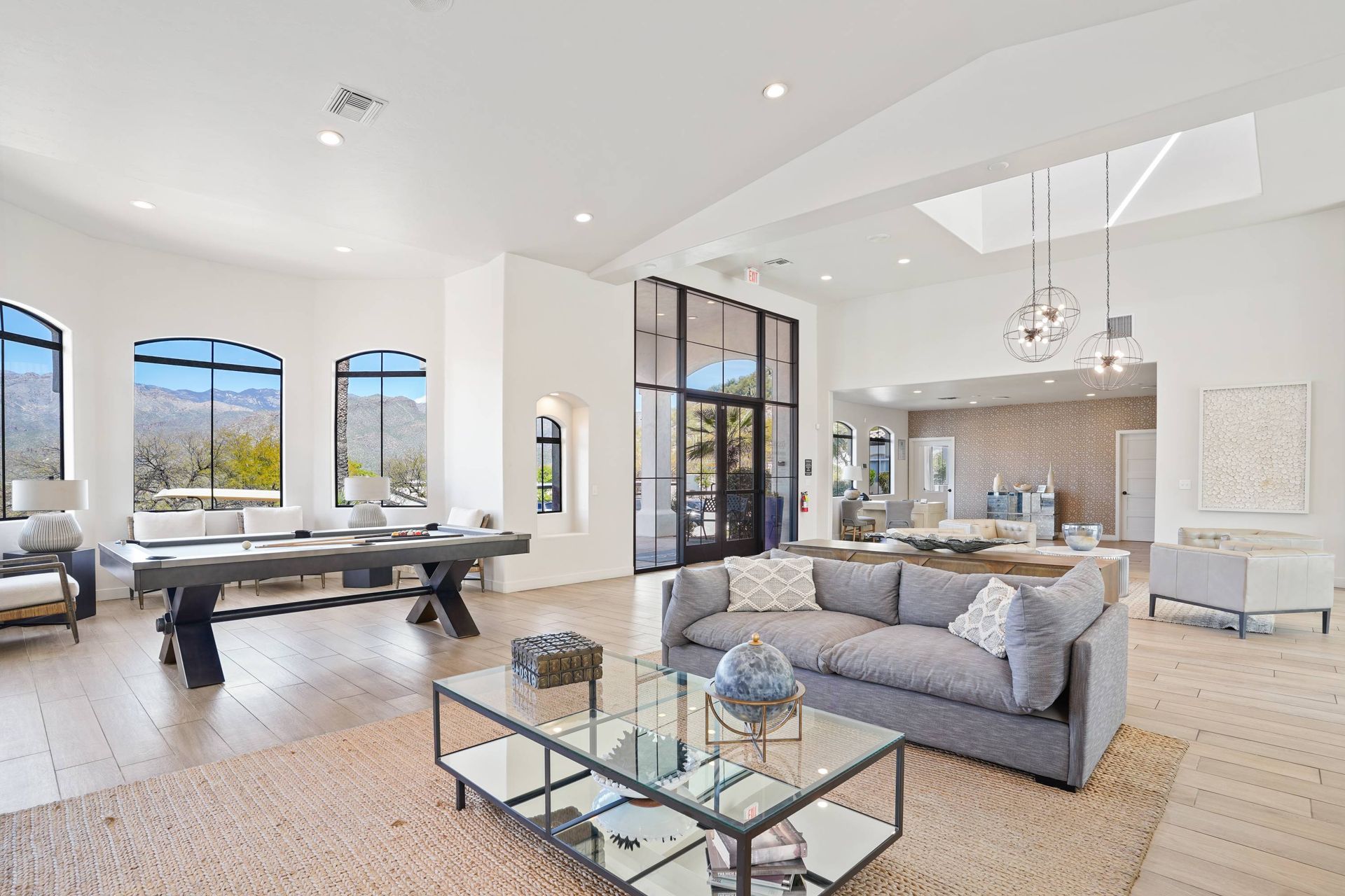 Bright communal lounge with arched windows, a pool table, and modern seating.