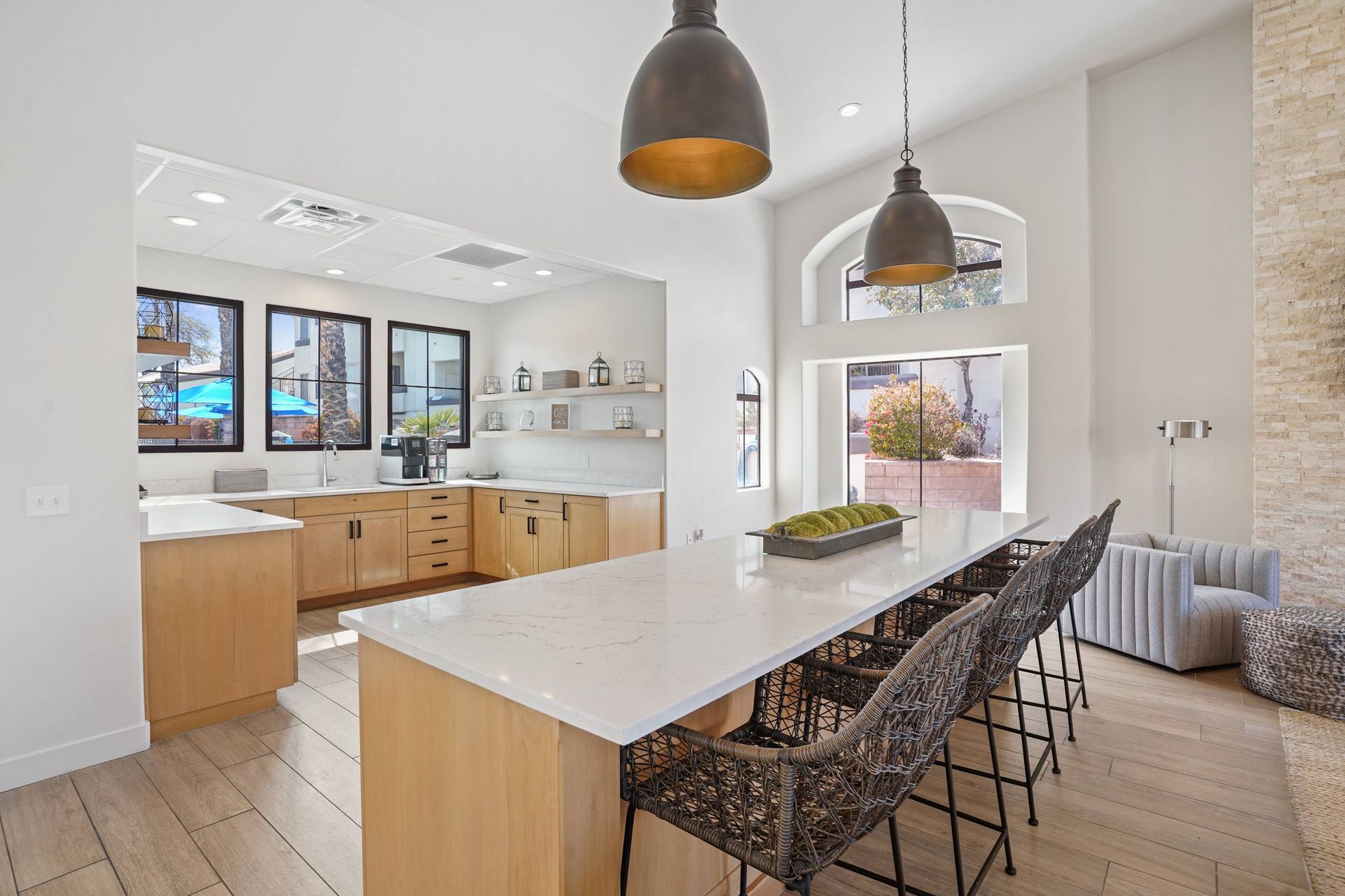 Bright communal kitchen with a marble island, bar seating, and large windows.