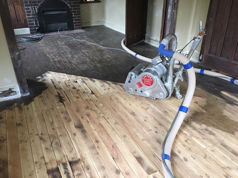 A sander is sitting on a wooden floor in a living room.