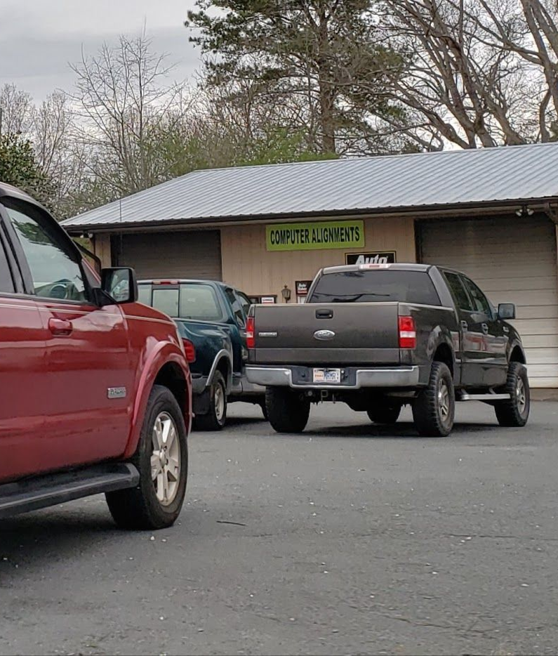 Red SUV and gray truck parked in front of the shop | Lowry Auto Service
