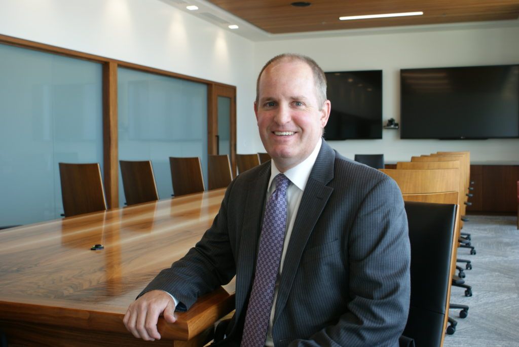 A man in a suit and tie is sitting in a conference room